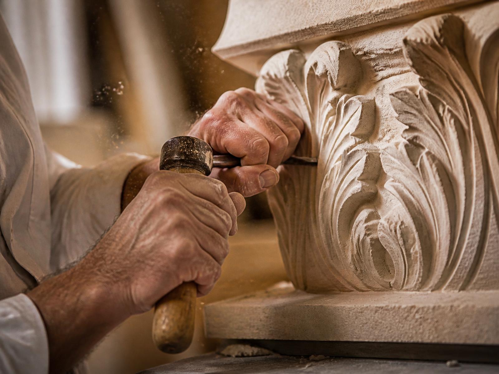 Artisan hand-carving a decorative detail into limestone